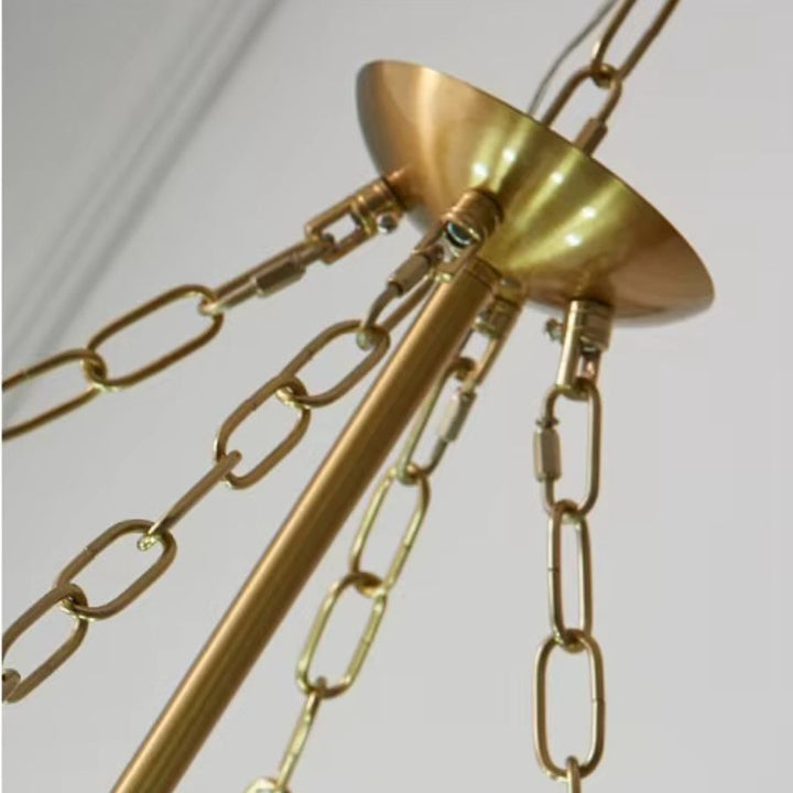 Gros plan sur la fixation dorée et les chaînes métalliques d'un lustre à perles au style Art déco élégant.