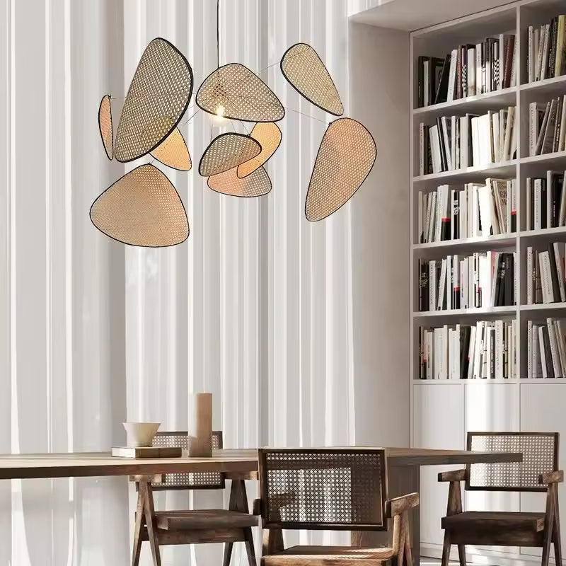 Au-dessus d’une table en bois et cannage, le luminaire aux pétales tressés en cannage souligne un décor naturel et raffiné