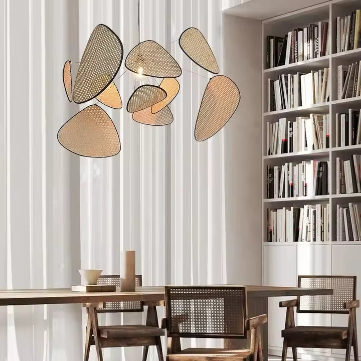 Au-dessus d’une table en bois et cannage, le luminaire aux pétales tressés en cannage souligne un décor naturel et raffiné
