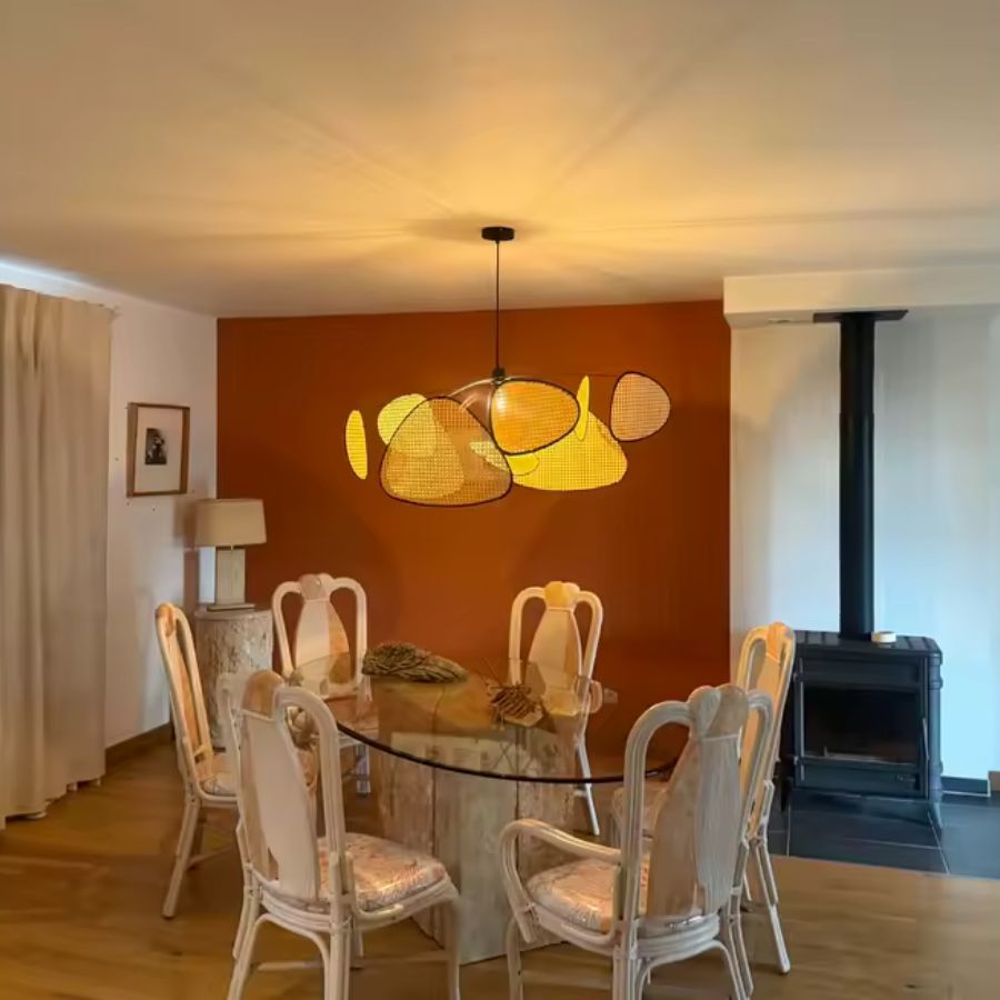 Éclairé d’une lumière chaude, le lustre aux pétales tressés anime une salle à manger terracotta au style contemporain