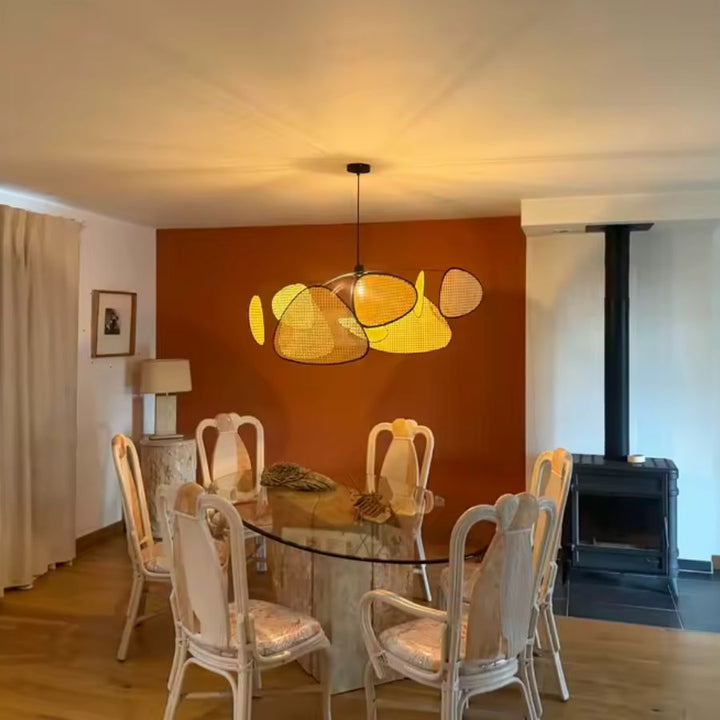 Éclairé d’une lumière chaude, le lustre aux pétales tressés anime une salle à manger terracotta au style contemporain