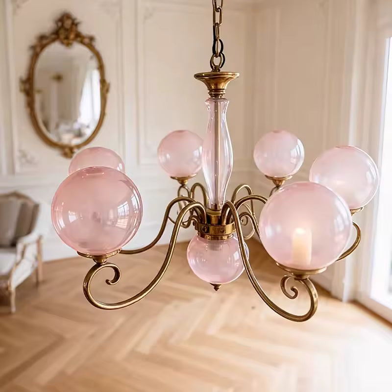Lustre rose à multiples globes en verre et volutes dorées, au style baroque élégant et décoratif