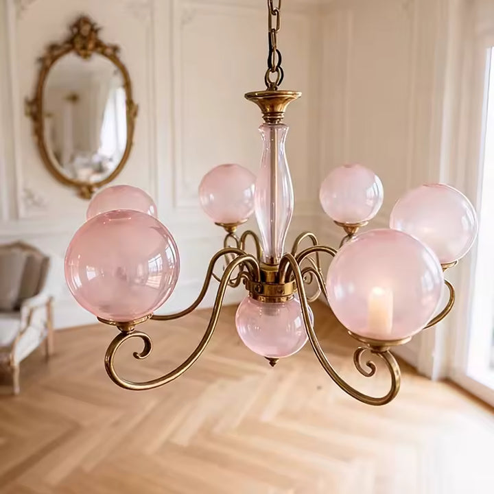 Lustre rose à multiples globes en verre et volutes dorées, au style baroque élégant et décoratif