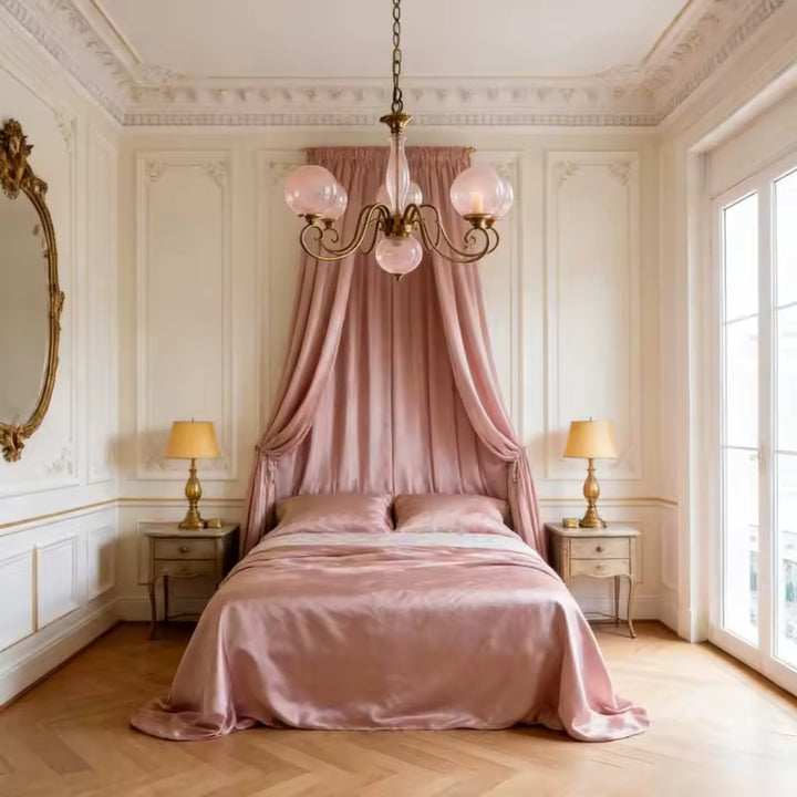 Lustre rose poudré à globes en verre dans une chambre romantique, avec volutes dorées au charme classique raffiné