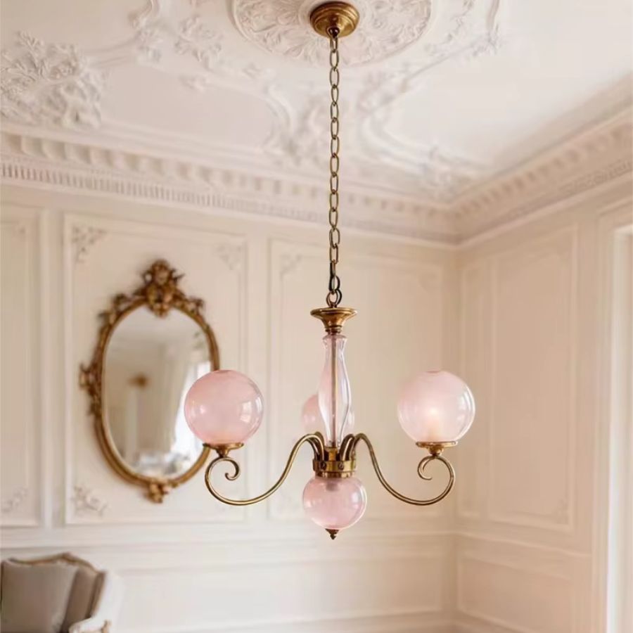 Lustre rose poudré à globes en verre suspendu par chaîne dorée, dans un intérieur classique au charme rétro raffiné