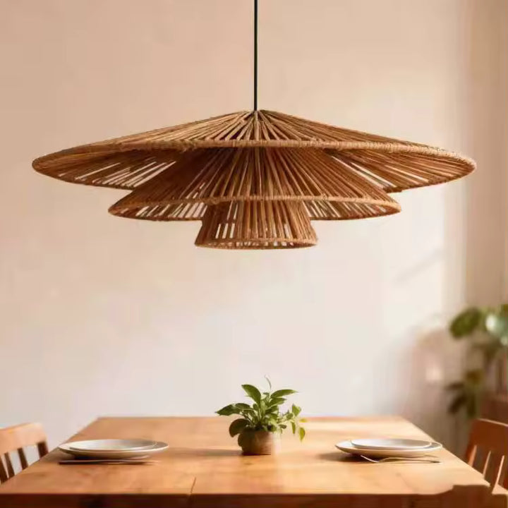 Trois abat-jour coniques en rotin ajouré composent une suspension naturelle au style bohème chic, au-dessus d'une table en bois.