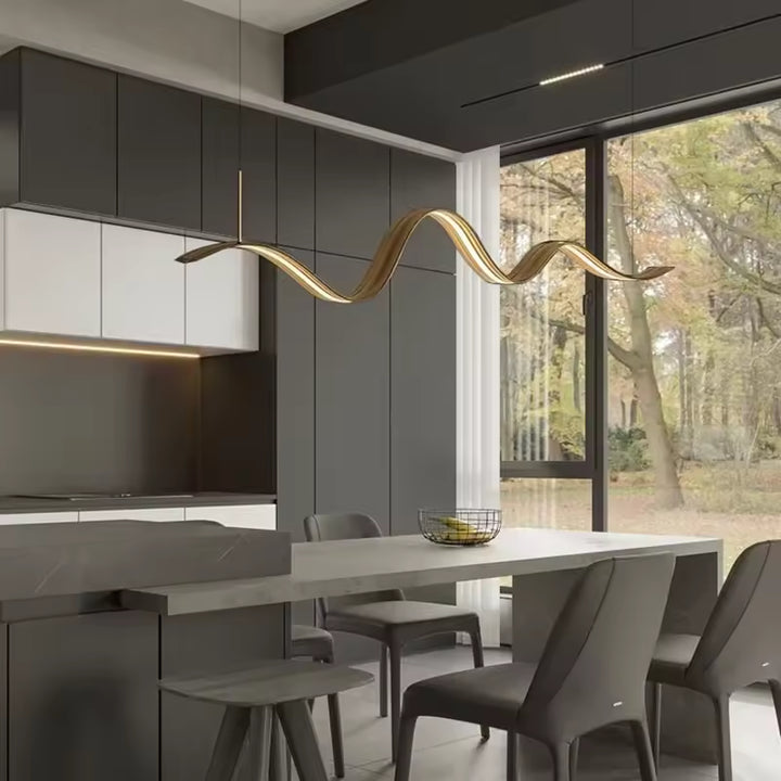 Dans cette cuisine contemporaine, le lustre ruban LED doré déploie une ligne ondulée fluide au-dessus de la table