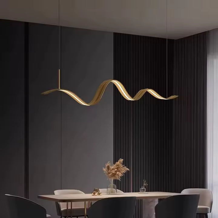 Dans une salle à manger contemporaine, le lustre ruban LED doré dessine une courbe élégante et sculpturale