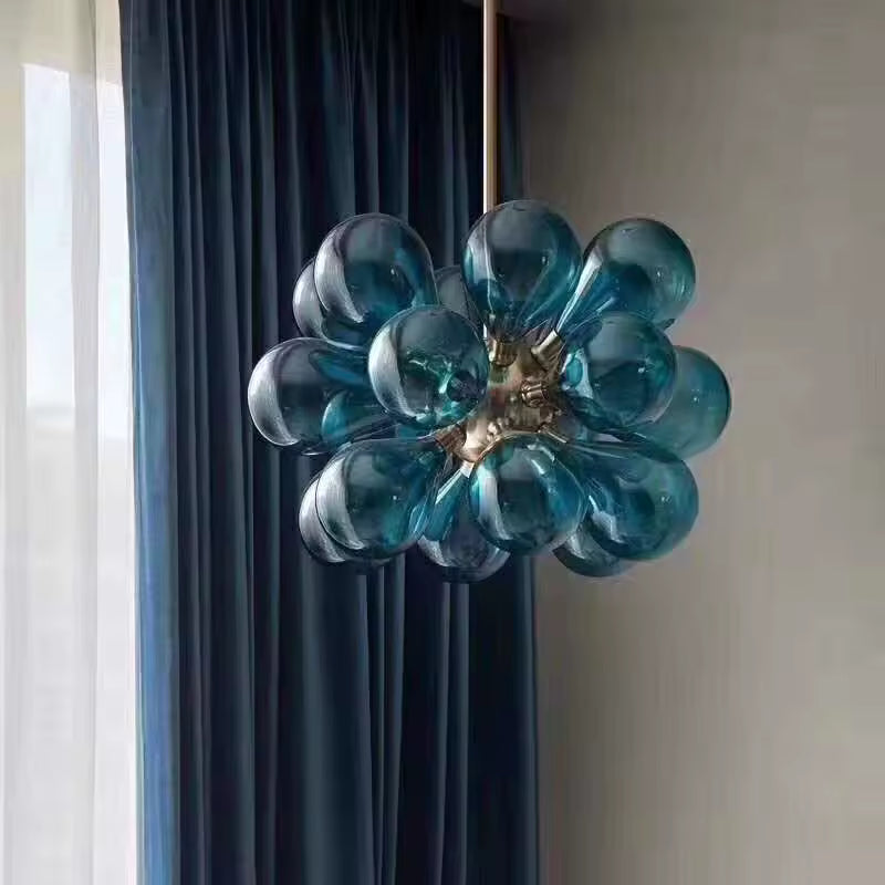 Vue rapprochée d'un lustre sculptural à 18 globes en verre bleu pétrole, au design organique inspiré du style rétro.