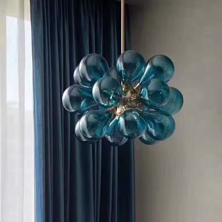Vue rapprochée d'un lustre sculptural à 18 globes en verre bleu pétrole, au design organique inspiré du style rétro.