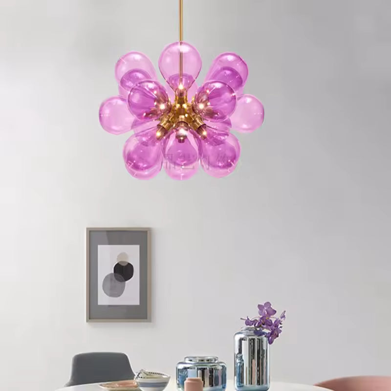 Suspension sculpturale à 18 globes en verre rose translucide et métal doré, au style pop vintage, dans une salle à manger.