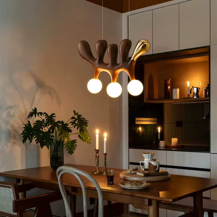 Dans une salle à manger chaleureuse, ce lustre sculptural en bois foncé associe trois globes lumineux