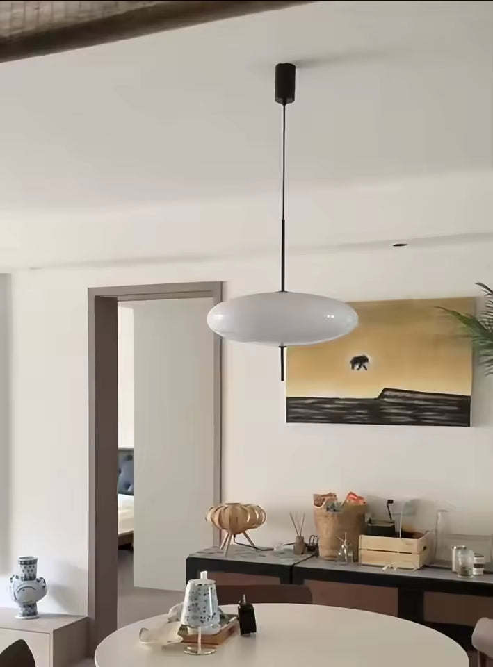 Lustre soucoupe blanche au design contemporain et épuré, suspendu au-dessus d’une table ronde dans un intérieur moderne