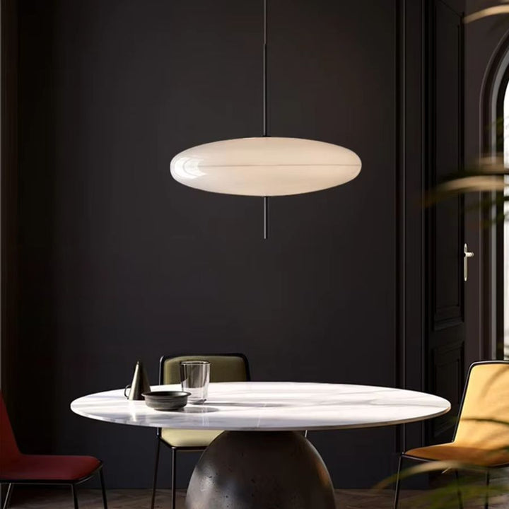 Lustre soucoupe blanche au design contemporain et raffiné, suspendu au-dessus d’une table ronde dans un intérieur sombre