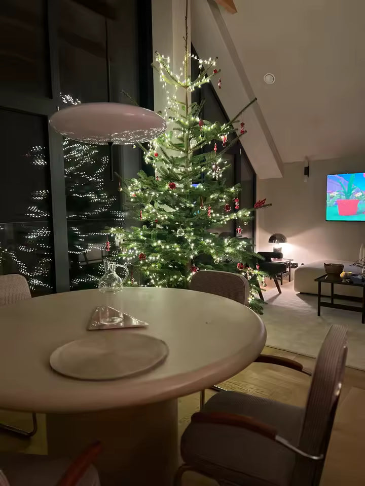 Lustre soucoupe blanche au design rétro-futuriste, suspendu au-dessus d’une table dans une salle à manger chaleureuse