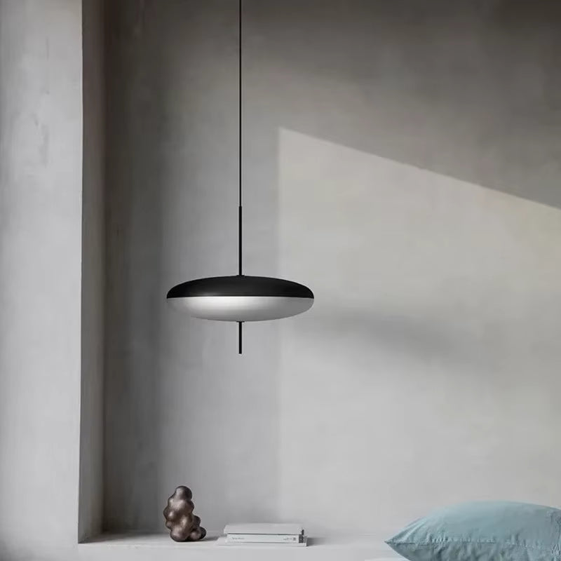 Lustre soucoupe noir et blanc au design minimaliste et futuriste, suspendu dans une chambre contemporaine épurée