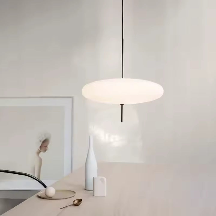 Lustre soucoupe volante blanc au design minimaliste, suspendu dans un intérieur épuré aux tons clairs