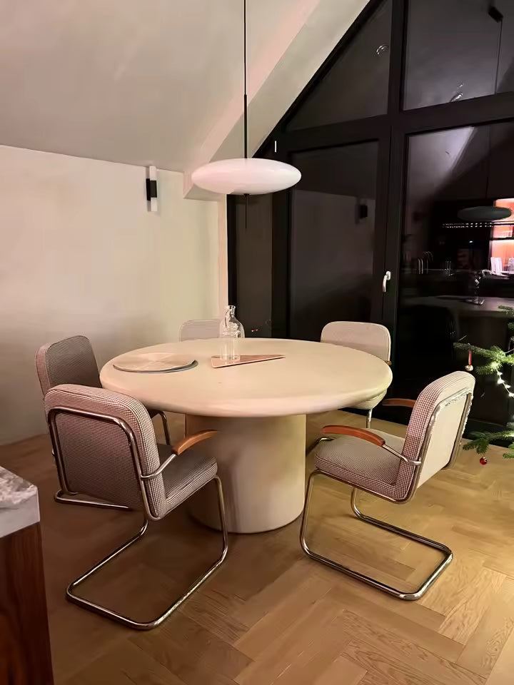 Lustre soucoupe volante blanche au design rétro contemporain, suspendu au-dessus d’une table ronde de salle à manger
