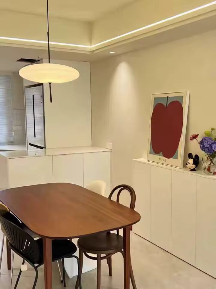 Lustre soucoupe volante blanche au style contemporain et épuré, suspendu au-dessus d’une table de salle à manger