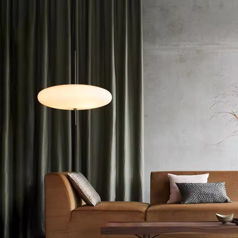 Lustre soucoupe volante blanche au style contemporain et épuré, suspendu dans un salon aux tonalités chaleureuses