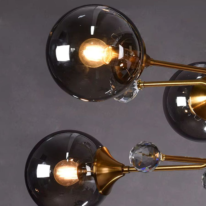 Gros plan sur les globes en verre fumé d'un lustre Spoutnik, avec bras dorés et ornements cristallins au style vintage.