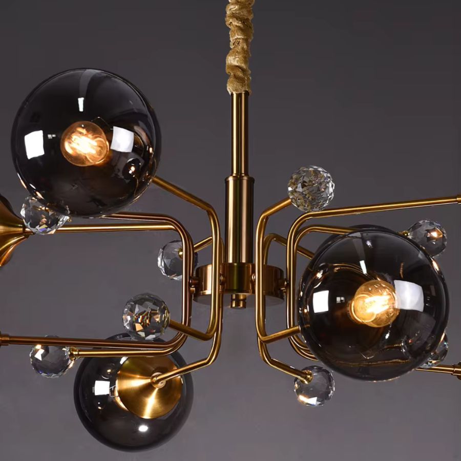 Vue rapprochée d'un lustre Spoutnik aux bras dorés géométriques, globes en verre fumé et cristaux décoratifs, style années 60.