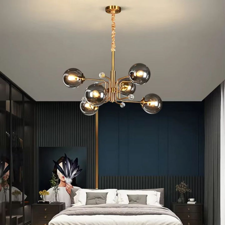 Au-dessus d'un lit, lustre Spoutnik doré à 6 globes en verre fumé, apportant une touche Mid-Century à une chambre moderne.