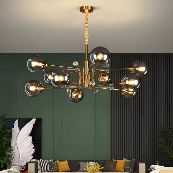 Dans un salon vert foncé, lustre Spoutnik doré aux globes en verre fumé, inspiré du design atomique des années 60.