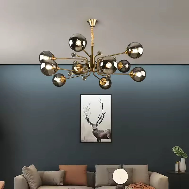Suspendu dans un salon aux murs bleu-gris, ce lustre Spoutnik doré à 10 globes fumés évoque le design Mid-Century.