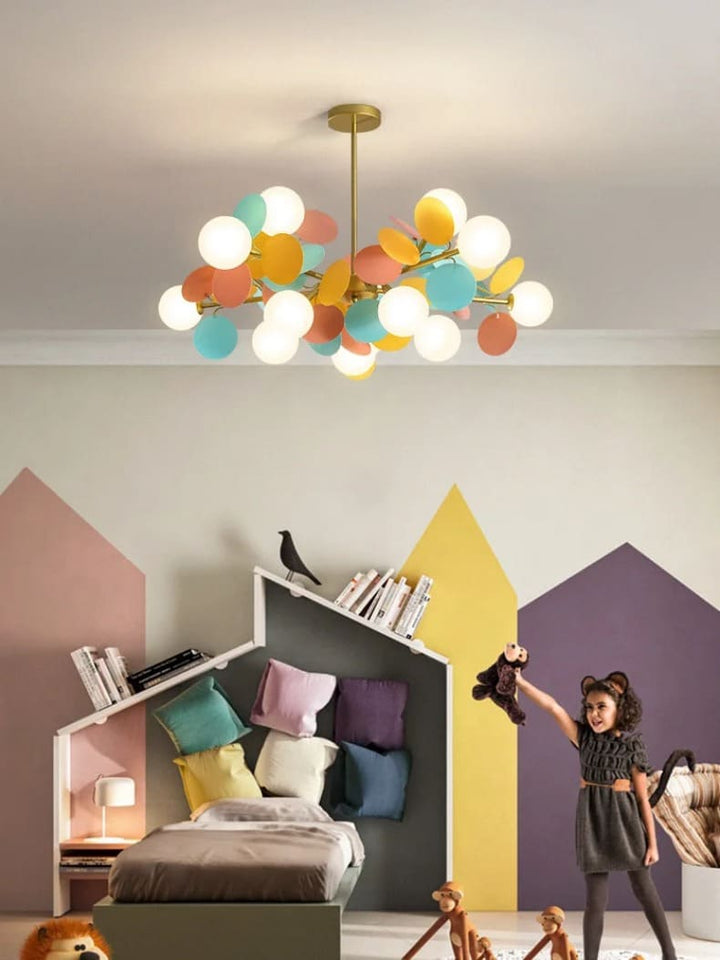 Suspension lumineuse aux pastilles colorées créant une atmosphère féerique dans une chambre de petite fille.