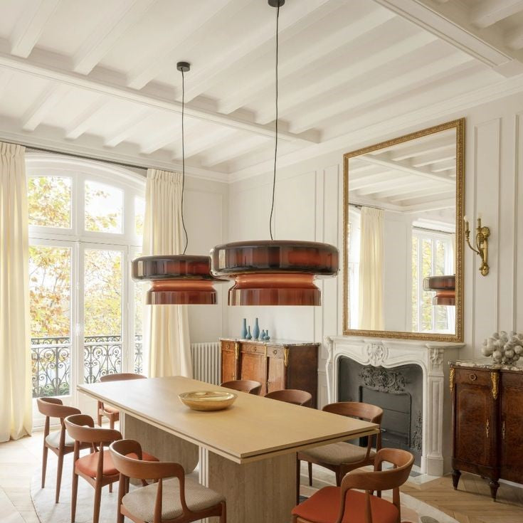 Lustre suspendu design en verre fumé rouge brun illuminant une vaste salle à manger élégante