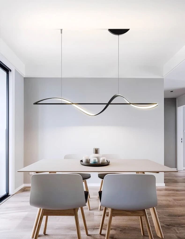 Lustre suspendu noir au design minimaliste illuminant une table de salle à manger moderne.