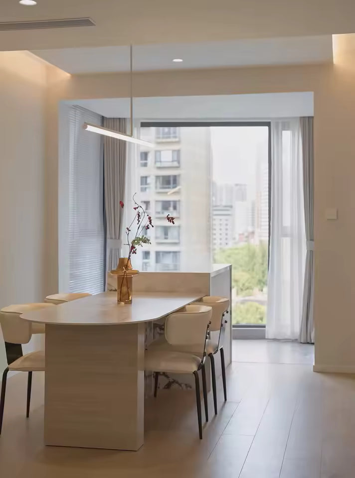 Au-dessus de la table à manger, un lustre tube LED linéaire souligne un intérieur minimaliste et contemporain.