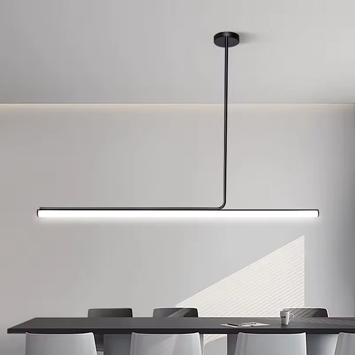Ligne lumineuse très épurée pour ce lustre tube noir LED, installé au-dessus d’une table dans un décor contemporain.