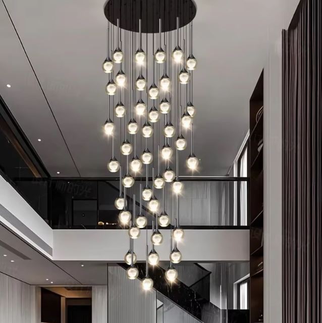 Lustre XXL en cascade pour plafond haut, globes en verre transparent à cœur opalin, style luxe moderne.