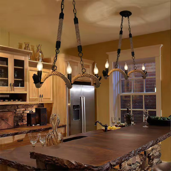 Deux lustres en corde de chanvre aux bras ondulés éclairent un îlot de cuisine en bois et pierre au style campagne chic.