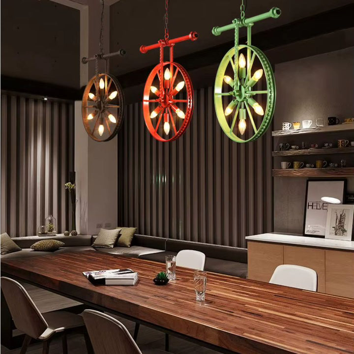 Trois lustres roue colorés à 6 lumières au-dessus d’une grande table en bois, entre style industriel et loft contemporain