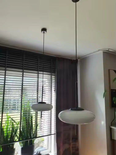 Deux lustres soucoupe blanche au design contemporain, suspendus dans un intérieur moderne et lumineux