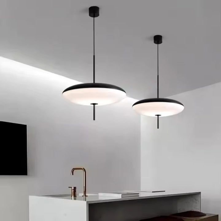 Deux lustres soucoupe noir et blanc au design minimaliste, suspendus au-dessus d’un îlot de cuisine contemporain