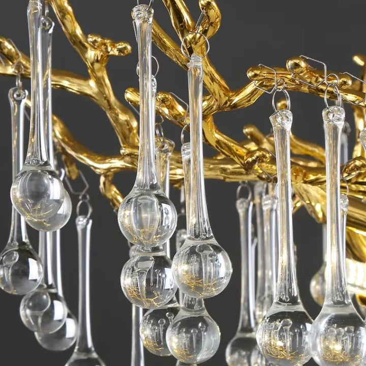 Vue rapprochée des pampilles de cristal en forme de goutte suspendues aux branches dorées sculpturales du luminaire