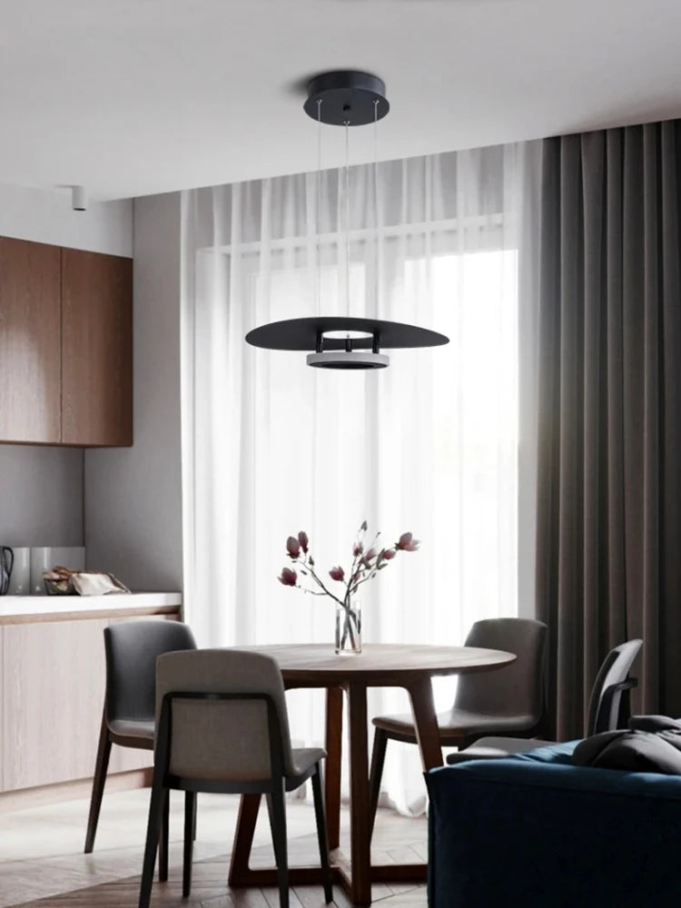 Élégante suspension disque à anneau lumineux éclairant une table à manger en bois naturel.
