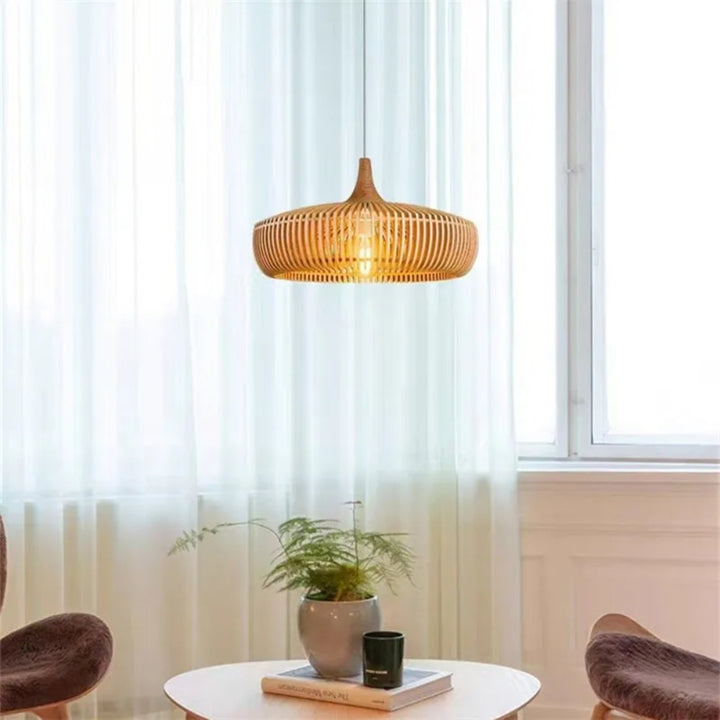 Suspension en bois ajouré placée près d'une grande fenêtre dans un décor épuré.