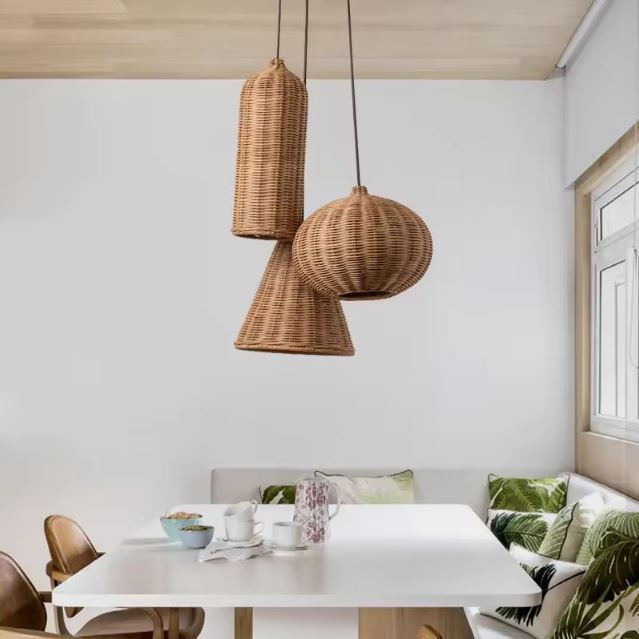 Trio de petites suspensions en rotin naturel suspendues au-dessus d'une table de déjeuner dans une cuisine lumineuse et moderne.