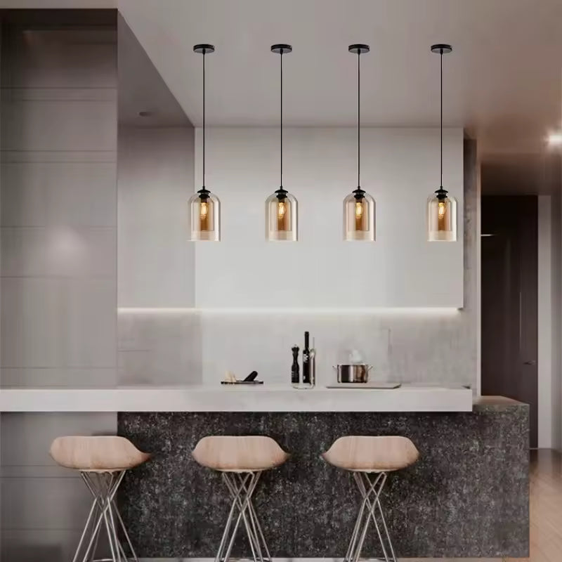 Quatre suspensions en verre ambré aux lignes arrondies illuminent un îlot de cuisine dans un esprit contemporain chic.