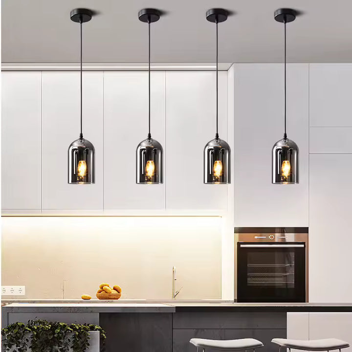 Alignées dans une cuisine épurée, quatre suspensions en verre fumé aux reflets chromés offrent un éclairage chaleureux et design.