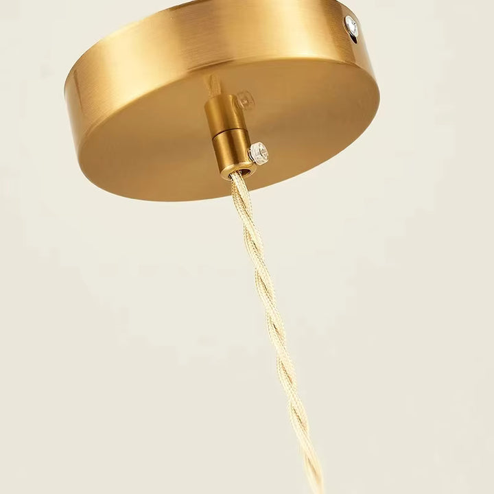 Détail de la rosace dorée et du câble torsadé d’une suspension fleur au style vintage raffiné