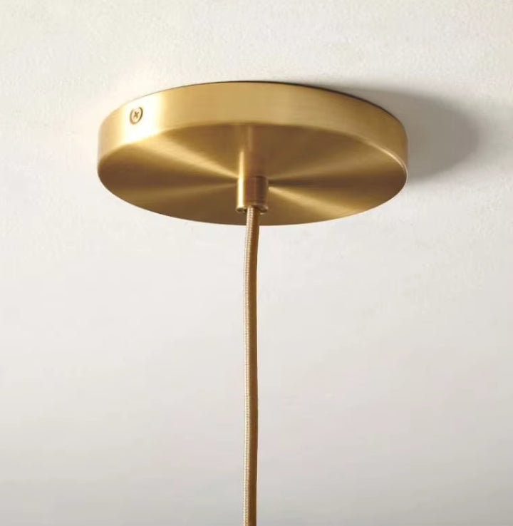 Détail de la rosace dorée d’une suspension globe en verre, avec finition élégante et contemporaine