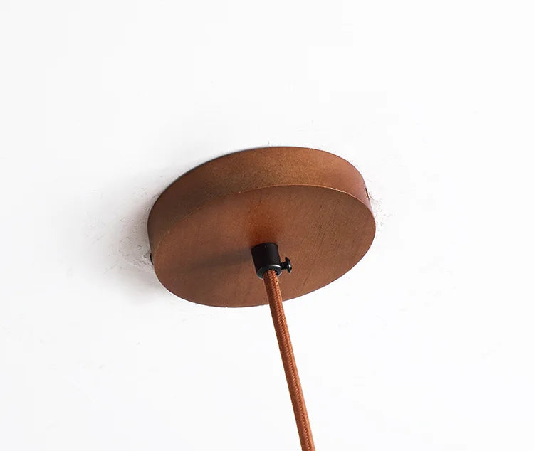Rosace de plafond ronde en bois assortie au cordon textile d'alimentation de la suspension en travetin.