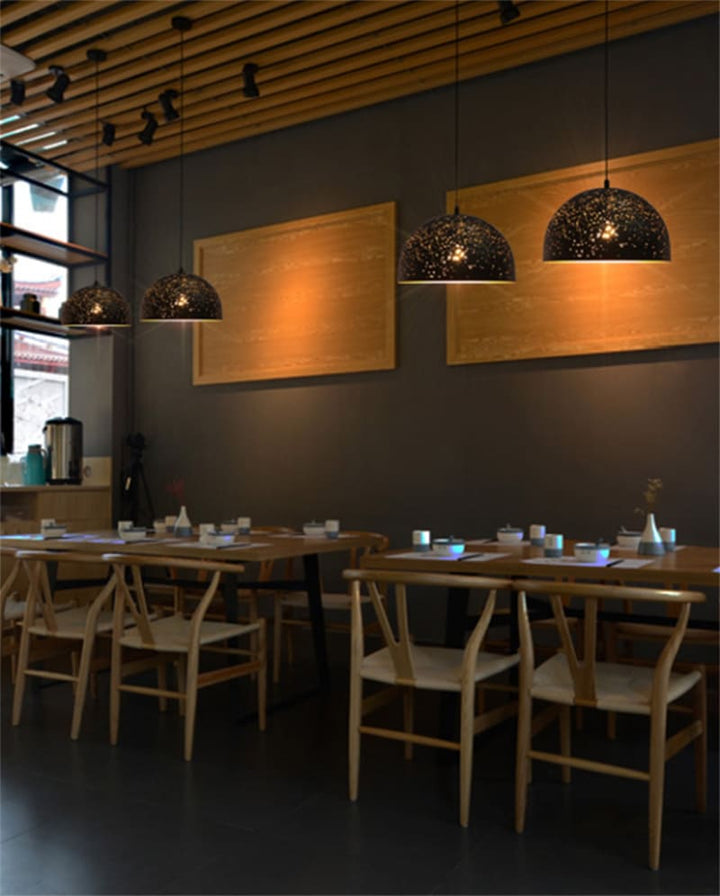Grande salle de restaurant aménagée avec des suspensions constellation perforées en métal design.