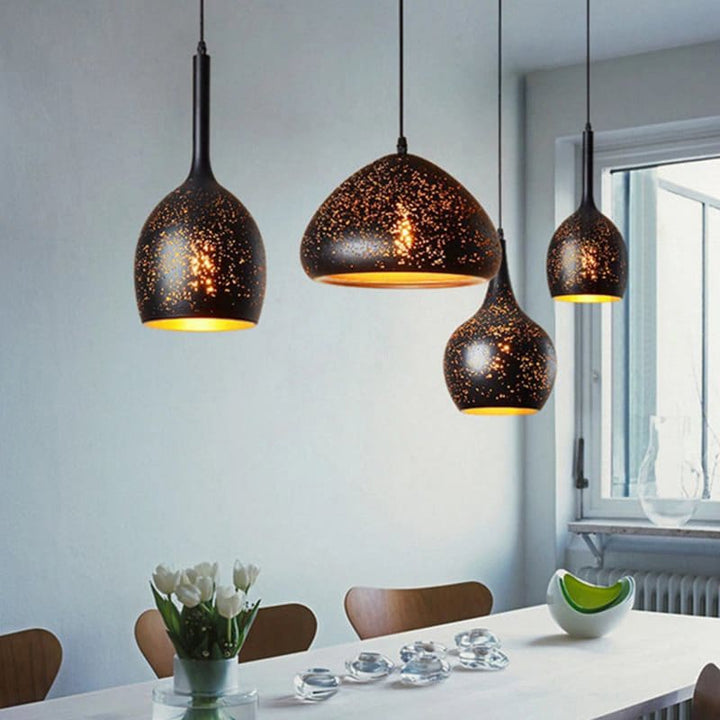 Salle à manger baignée de lumière naturelle avec un ensemble de suspensions constellation perforées.